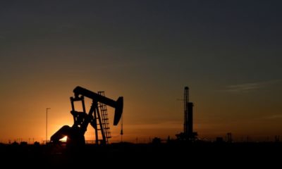 FILE PHOTO: A pump jack operates in front of a drilling rig at sunset in an oil field in Midland